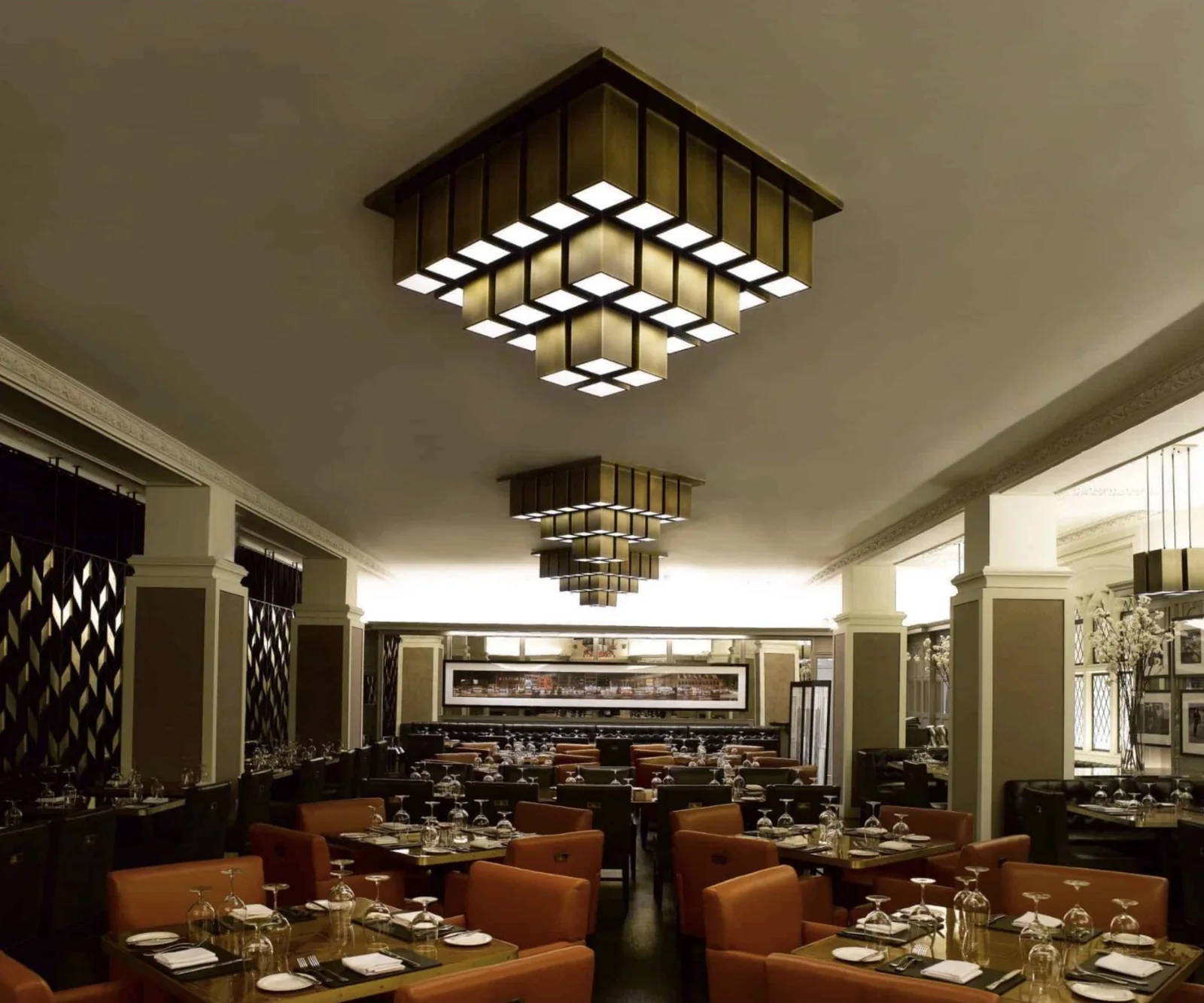 Dining room with two stacked square brass pendants hanging over the tables